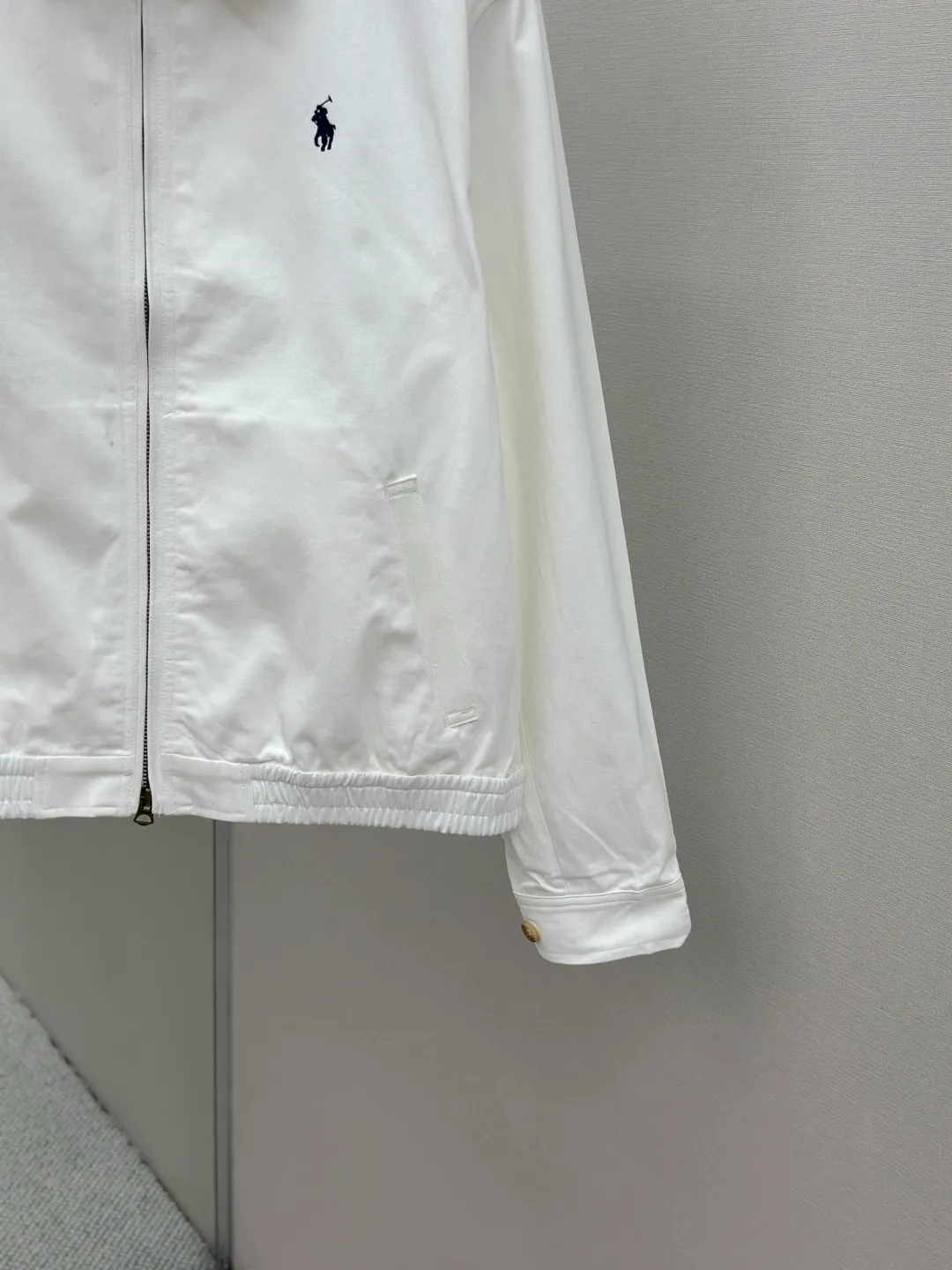 P480 Ralph Lauren embroidered zipper jacket. Customized cloud-velvet white twill cotton. Soft and silky. Comfortable against the skin. Dressed in pure white. Exuding innate elegance. Exquisite indigo pony logo embellished with it. Fully recognizable. Bringing an atmosphere of freedom and vitality. Pure and smart color symphony. Reconstructing classics with neat silhouettes and defining modern relaxation with versatile genes. Process 1: Using imported machine embroidery technology. Use advanced computer control systems and precision mechanical components to achieve iconic pony embroidery operations with high precision and smooth and delicate lines. Process 2: Template machine bag opening. The preset template guides the position, shape and size of the bag opening. The accuracy ensures the quality of the bag opening effect. Process 3: The hem is made in one go using a three-needle waist-drawing machine. The elastic band and fabric are sewn together in the same process using the machine's special needle position and feeding mechanism. The three-needle design is stronger and can evenly distribute pressure. Ensure that the elastic band and the fabric are closely attached. Process 4: The fabrics are washed carefully and have a better hand feel. Not easy to deform, not easy to shrink, not easy to fade, and maintain long-term beauty. Accessories: Customized Ralph Lauren engraved buckle, Customized Ralph Lauren bronze zipper, Customized Ralph Lauren trademark. Version: Fitted version. Size: S M L XL